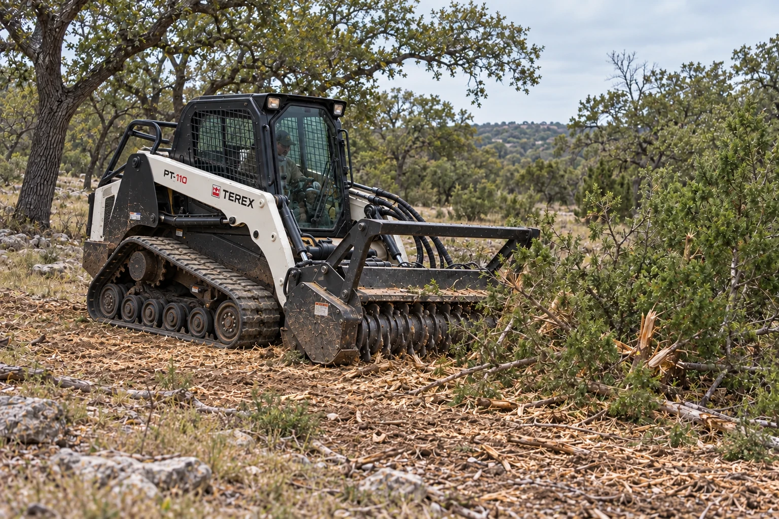 White and black Terex PT-110 mulching brush beside live oak trees